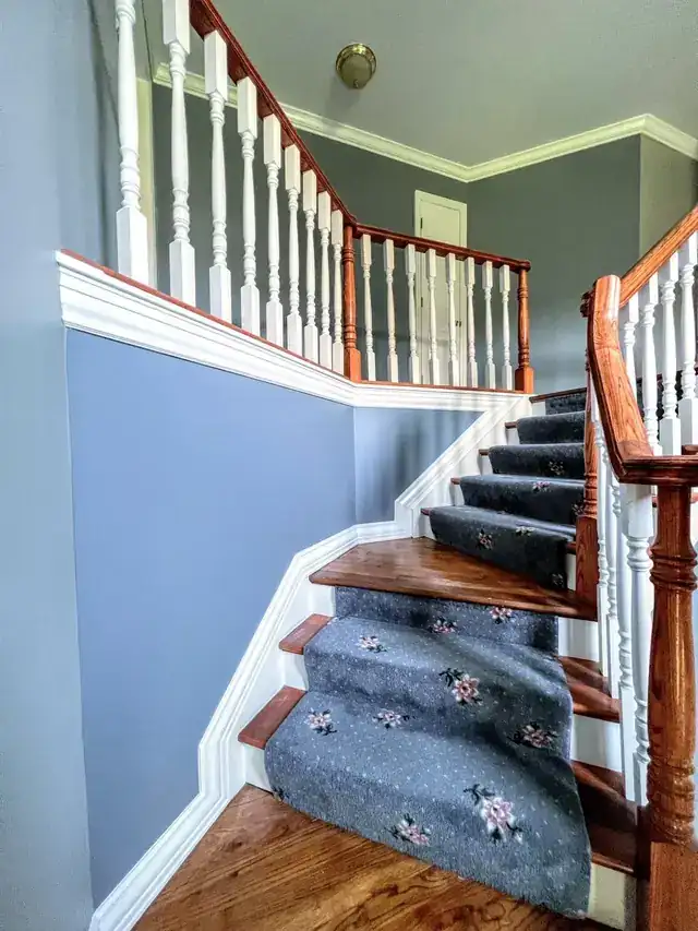 Staircase wall painted blue-grey above white wainscot