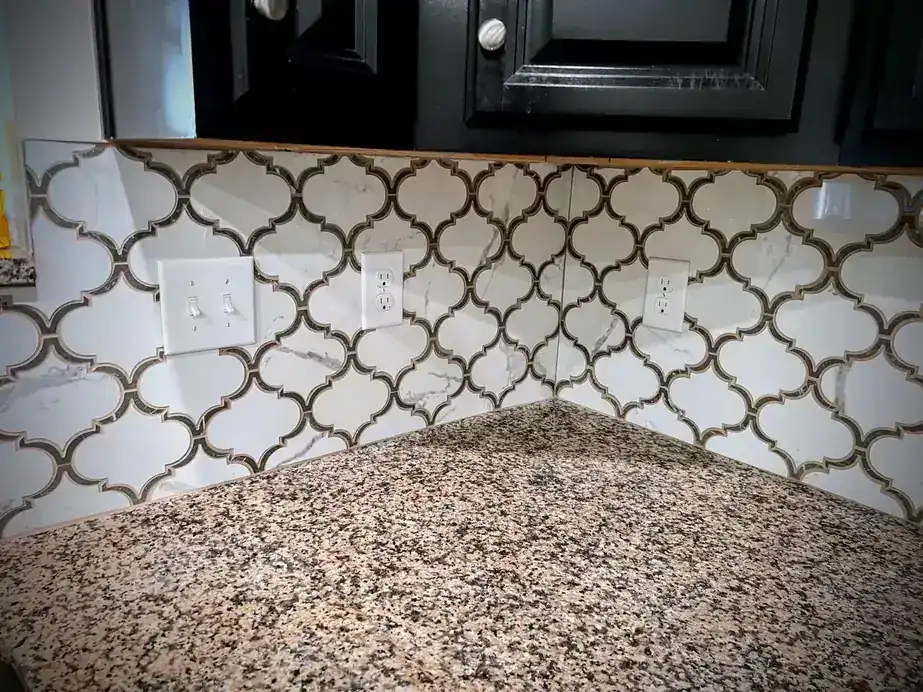 White arabesque tile backsplash above a granite counter