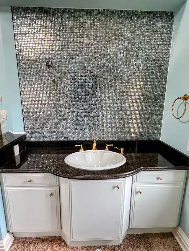 Mosaic tile wall behind a white bathroom vanity