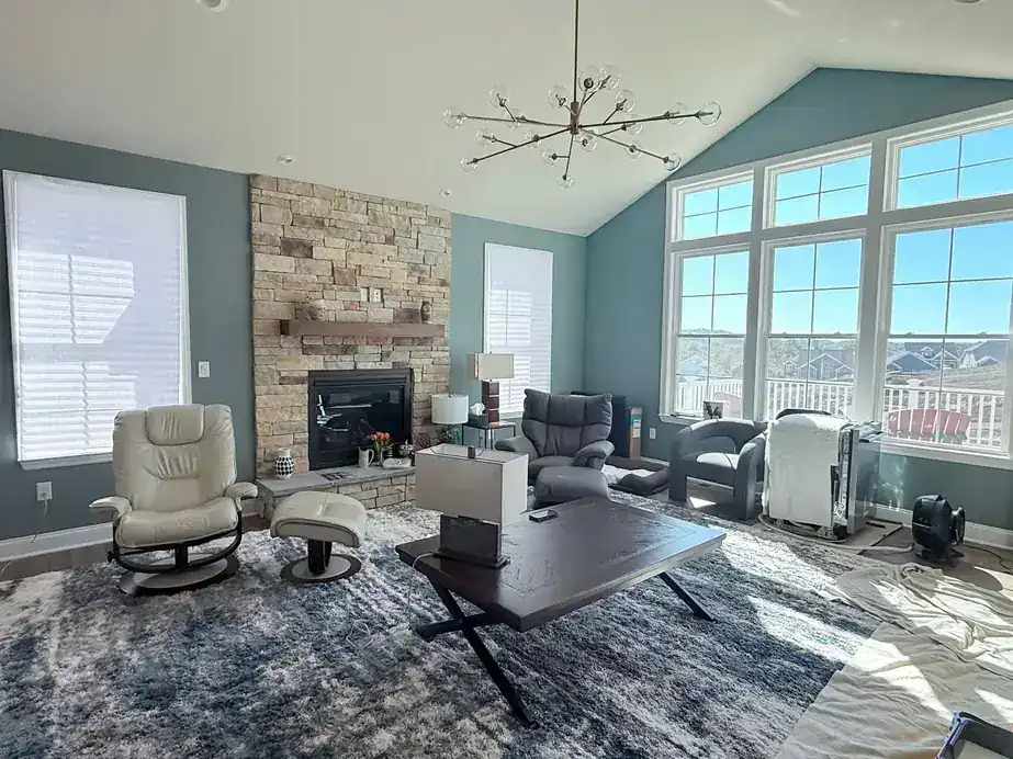Vaulted great room with slate-teal walls, white trim and a stone fireplace